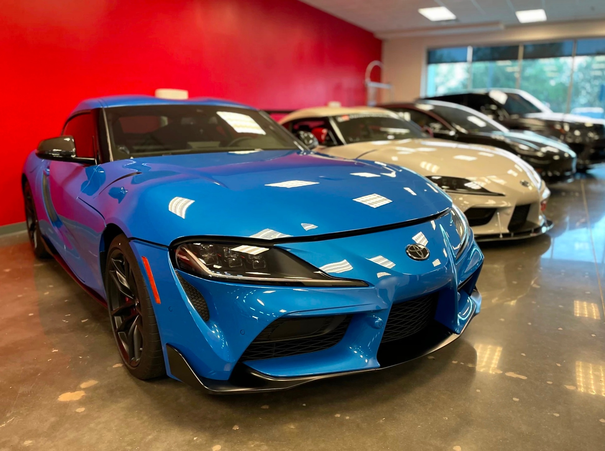 Blue and white Toyota Supra sports cars lined up inside an automotive workshop.
